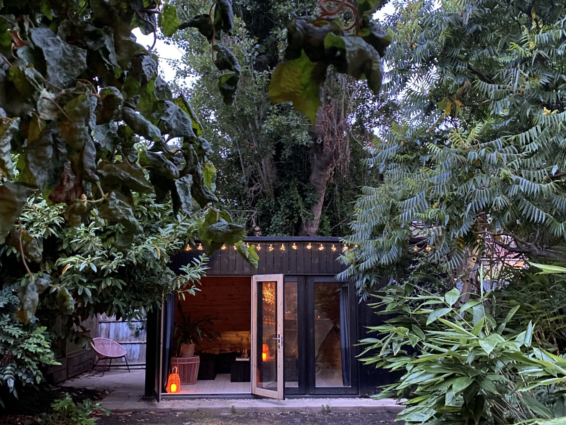 The garden sanctuary entrance in Honor Oak Park, lit by fairy lights among the trees in the evening